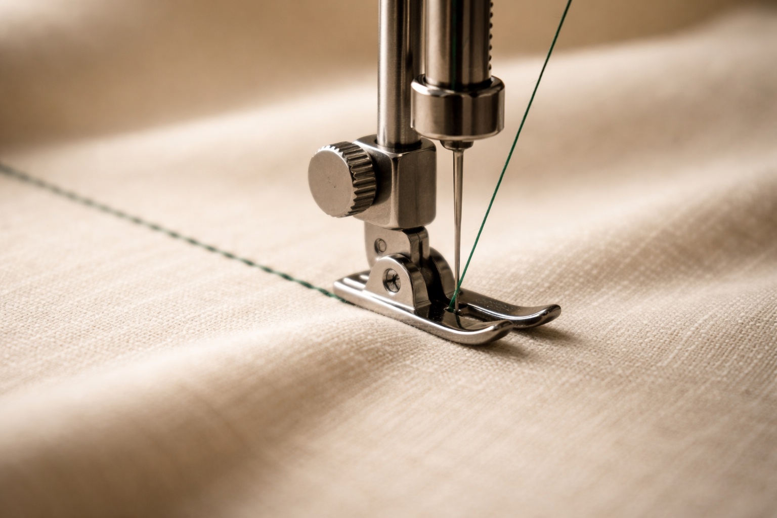 Sewing machine stitching emerald thread on cream linen